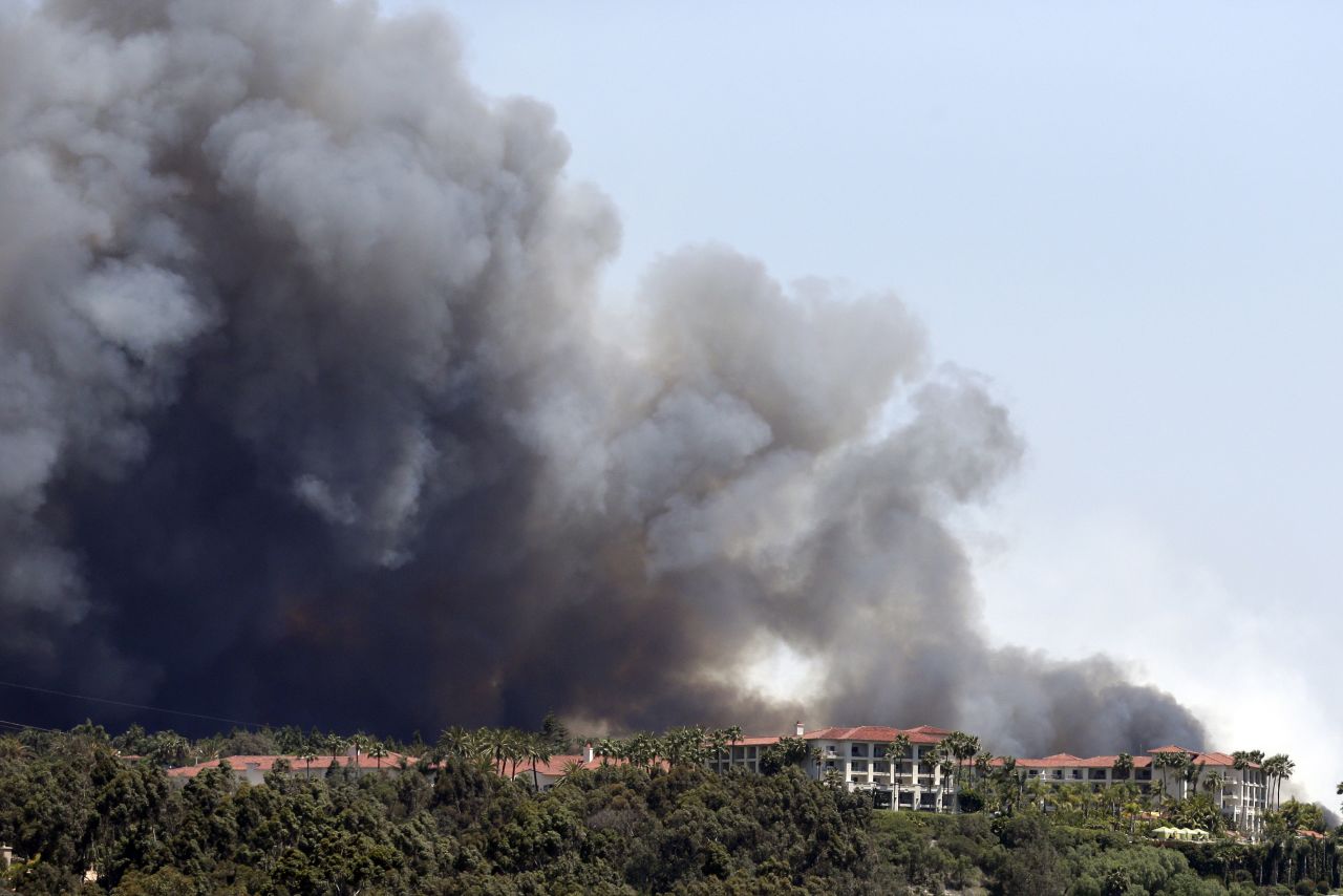 A wildfire approaches buildings in Carlsbad on May 14.