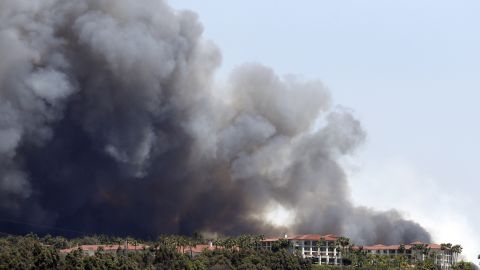 A wildfire approaches buildings in Carlsbad on May 14.