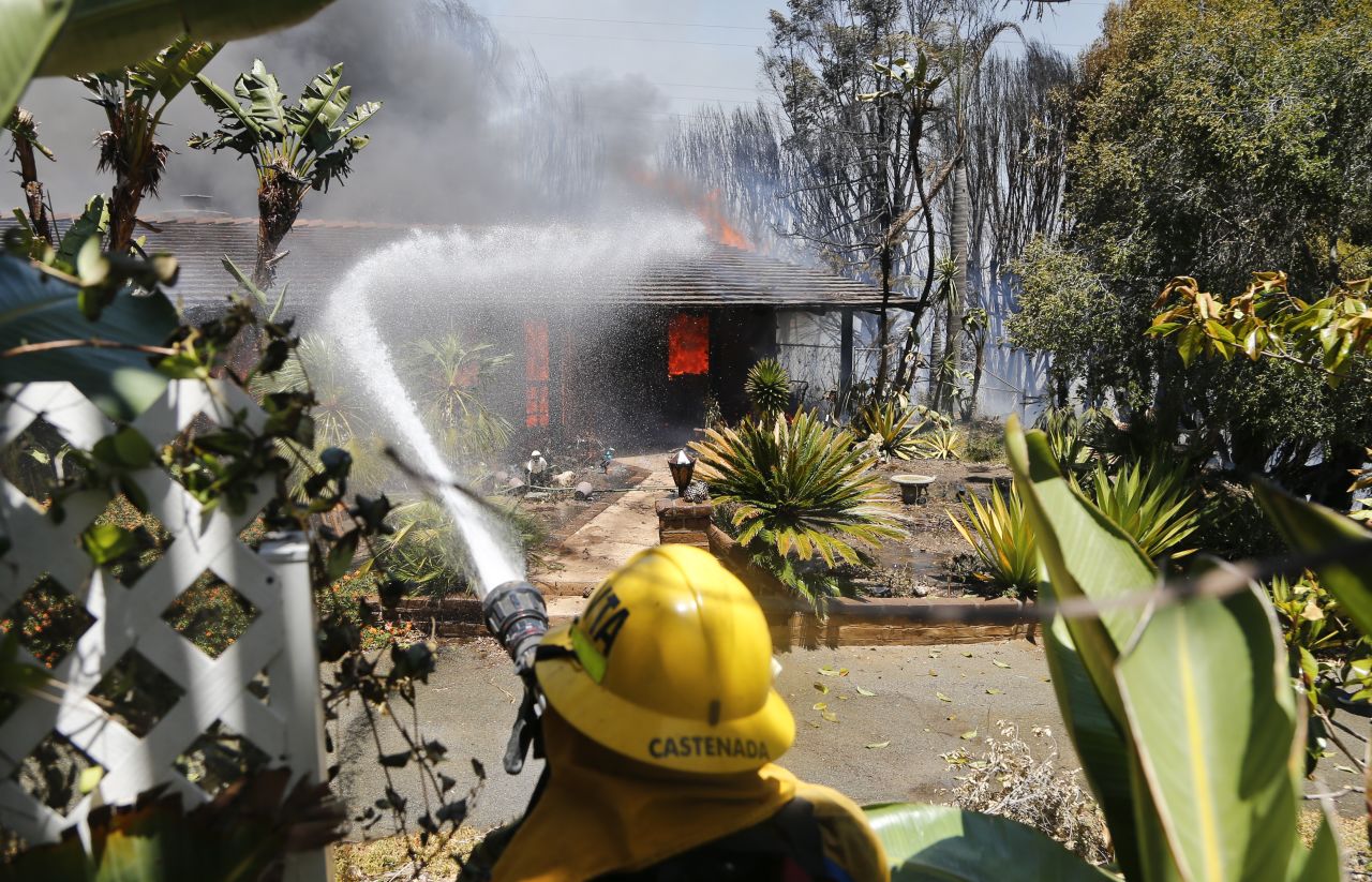 A firefighter sprays water onto a fully engulfed home in Carlsbad on May 14.