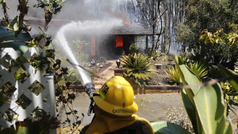 A firefighter sprays water onto a fully engulfed home in Carlsbad on May 14.