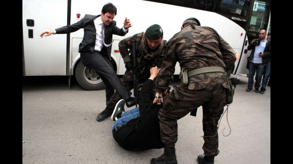 An aide to Turkish Prime Minister Recep Tayyip Erdogan kicks a person who is being wrestled to the ground by two police officers during protests in Manisa, Turkey, on Wednesday, May 14.