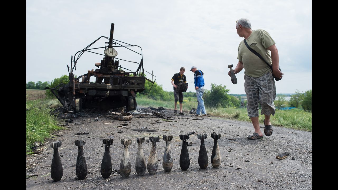 People collect mortar shells in front of a burnt-out Ukrainian military vehicle near Oktyabrskoe, Ukraine, on May 14.