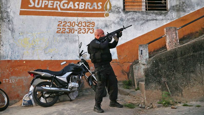 A Brazilian national police officer aims his weapon Tuesday, May 13, during a search for fugitives in the Complexo do Alemao favela of Rio de Janeiro. Brazil is trying to pacify Rio's favelas, or slums, ahead of next month's FIFA World Cup. 