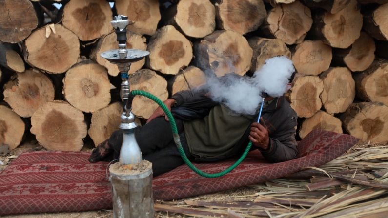 A Palestinian charcoal worker smokes during a tea break at a production facility in Gaza on Monday, May 12.