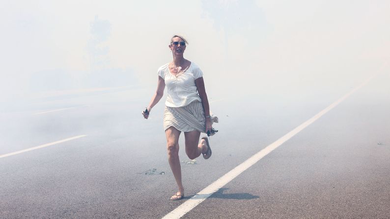 A woman flees a wildfire as it crosses a highway in Carlsbad, California, on Wednesday, May 14. <a href="http://www.cnn.com/2014/05/13/us/gallery/california-wildfire/index.html">Wildfires have forced evacuations</a> in San Diego County after a high-pressure system brought unseasonable heat and gusty winds to the parched state.