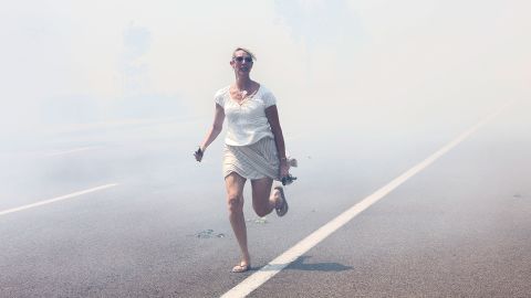 A woman flees a wildfire as it crosses a highway in Carlsbad on May 14.