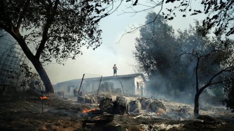 Jeff Brown wets down the roof of his Escondido home as a wildfire smolders around it on May 15.
