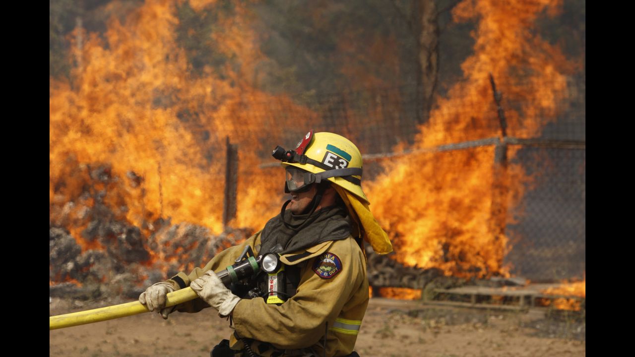 A firefighter pulls a hose on May 15 while battling a wildfire in San Marcos.
