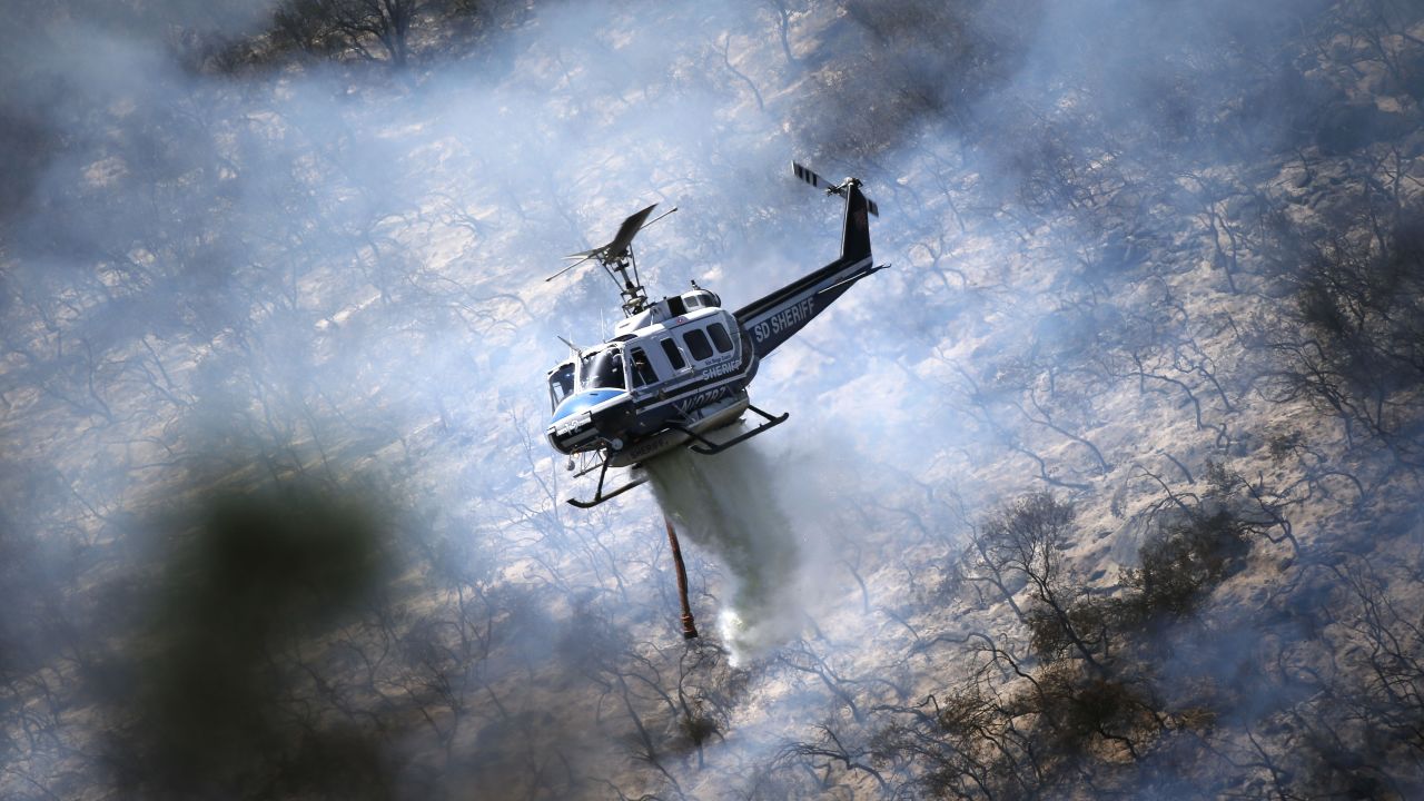 A helicopter from the San Diego County Sheriff's Department drops water on flames in the hills of San Marcos, California, on May 15.