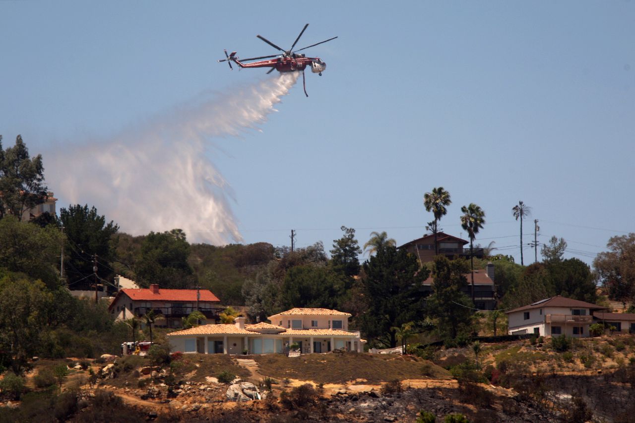 A helicopter drops water near homes in San Marcos, California, on May 16.