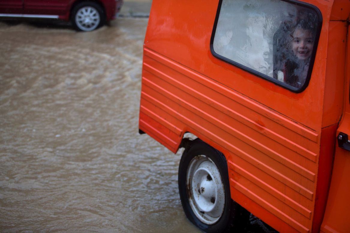 A child smiles from a car window on a flooded street in a suburb of Belgrade, Serbia, on Thursday, May 15.