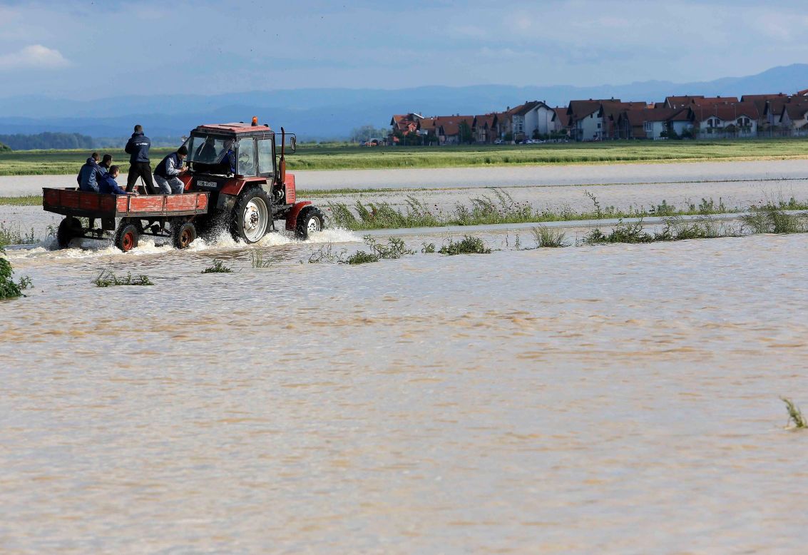 Residentes viajan en un carro tirado por un tractor a través de un campo inundado en la ciudad bosnia oriental de Bijeljina el 17 de mayo.
