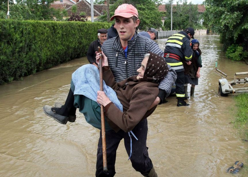 A rescuer carries an elderly woman out of her flooded house in Obrez, Serbia, on Saturday, May 17.