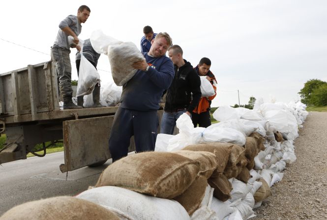 Residentes colocan sacos de arena en una carretera cerca Orasje, Bosnia, para proteger la ciudad de las inundaciones el domingo, 18 de mayo.