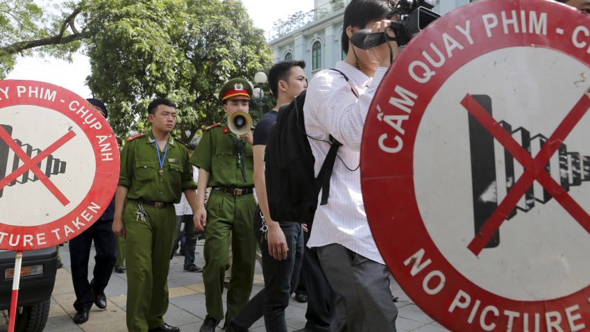 A Vietnamese police officer uses a speaker to order pedestrians including journalists to leave a closed area near the Chinese Embassy in Hanoi, Vietnam on Sunday, May 18, 2014.
