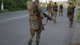 Pro-Russian militants walk to their positions to fight against Ukrainian government troops at a checkpoint blocking the major highway which links Kharkiv, outside Slovyansk, eastern Ukraine, Saturday, May 17, 2014.