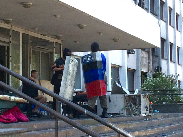 A handful of young men who say they support independence for this region of eastern Ukraine practice with riot shields on the steps of the ruined City Hall.