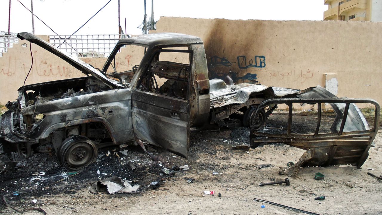 A burnt out vehicle is seen on the side of the road leading to the airport in Tripoli on May 19, 2014 following attacks by armed groups the previous day. 