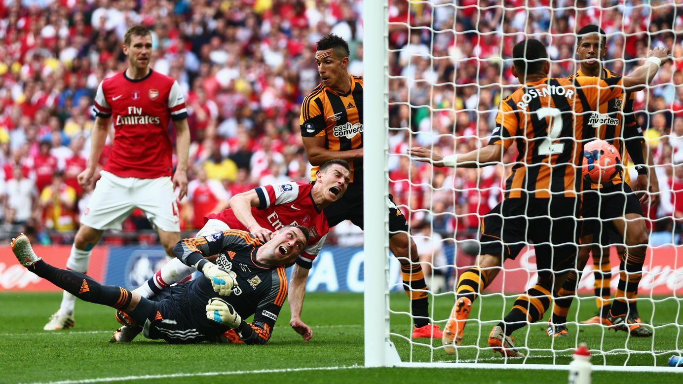 Arsenal's Laurent Koscielny falls over Hull City goalkeeper Allan McGregor as he scores a goal in the FA Cup final Saturday, May 17, in London. Arsenal won the game 3-2, collecting its first trophy since 2005.