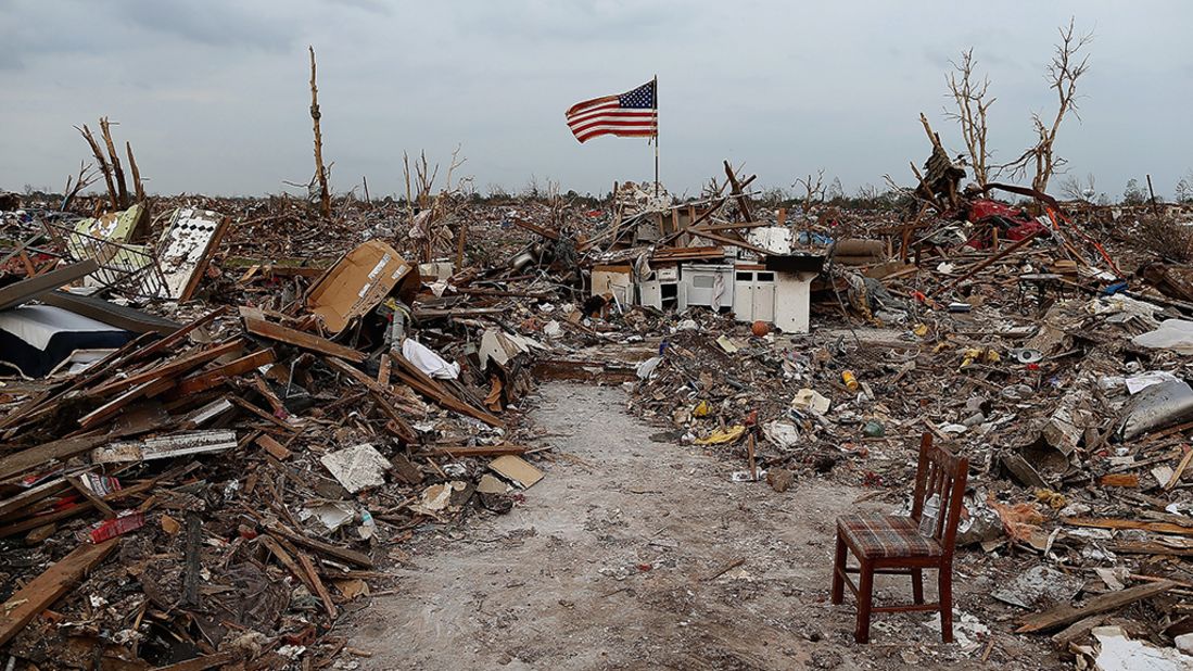 A massive tornado hit Moore, Oklahoma, on May 20, 2013, killing 24 people and causing an estimated $2 billion in property damage. Photographs taken then and now reveal the progress that has been made one year on. Here, an American flag flies over the rubble of a destroyed neighborhood in Moore on May 24, 2013. 