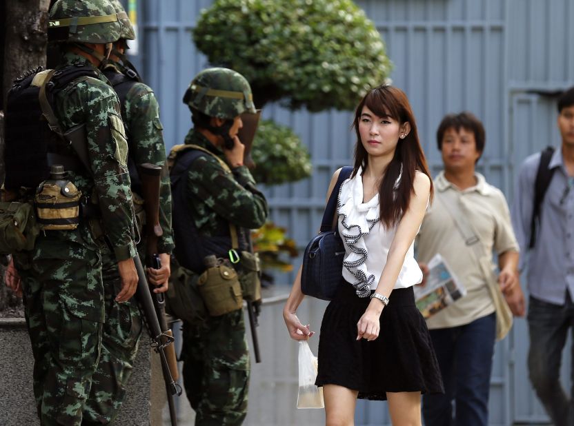 Office workers walk past armed soldiers outside the Shinawatra Tower Two office building in Bangkok on May 20.