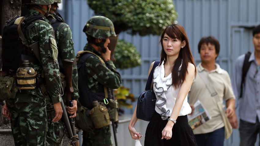 Office workers walk past armed soldiers outside the Shinawatra Tower Two office building in Bangkok on May 20.