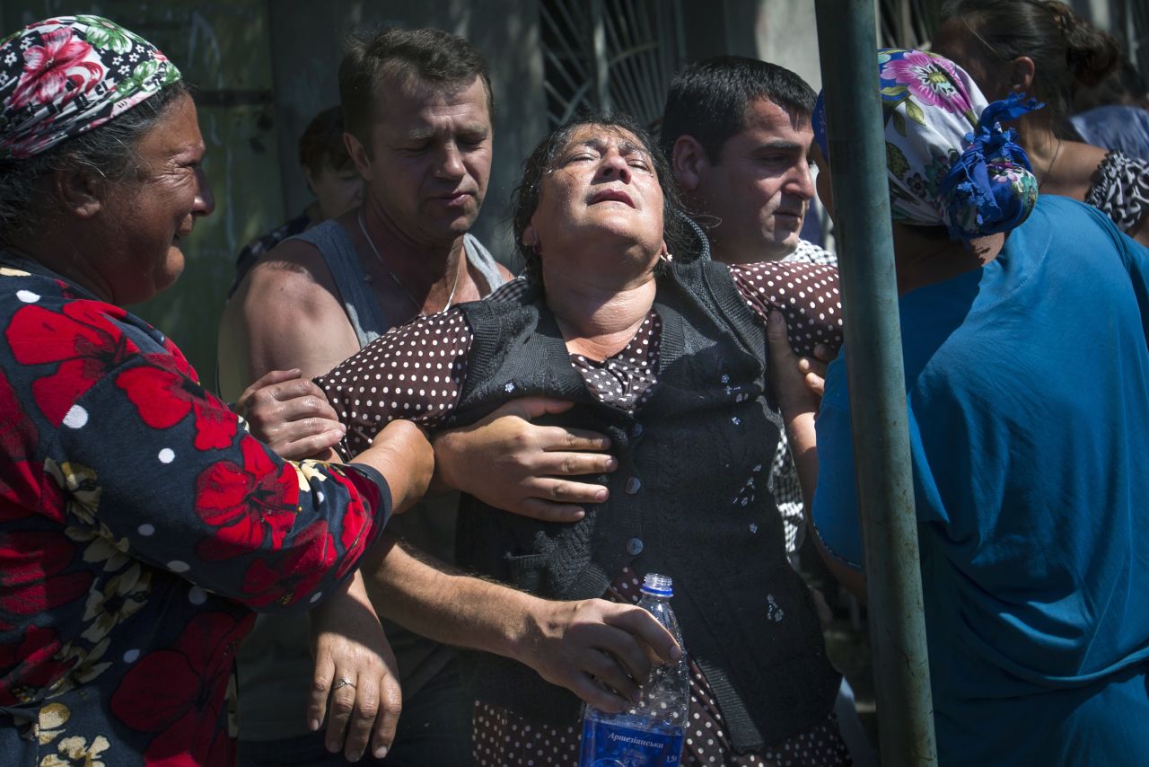 Local citizens help support a woman at a rally protesting shelling by Ukrainian government forces in the village of Semyonovka, Ukraine, on Thursday, May 22.