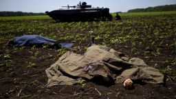 Bodies covered with blankets lie in a field near the village of Blahodatne, eastern Ukraine, on Thursday, May 22, 2014, as a Ukrainian soldier smokes next to his armored infantry vehicle. At least 11 Ukrainian troops were killed and about 30 others were wounded when Pro-Russians attacked a military checkpoint, the deadliest raid in the weeks of fighting in eastern Ukraine. Three charred Ukrainian armored infantry vehicles, their turrets blown away by powerful explosions, and several burned vehicles stood at the site of the combat. (AP Photo/Ivan Sekretarev)