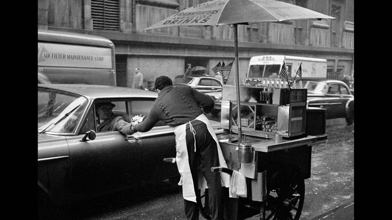 A man in New York buys a hot dog from his car window in Lower Manhattan in 1962.