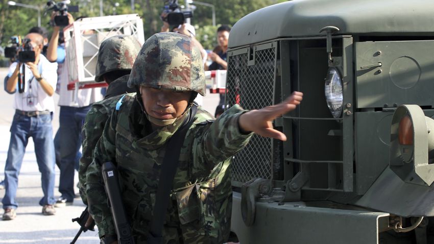 An armed Thai soldier orders journalists to step back as a military vehicle enters the compound of the Army Club after the military staged a coup Thursday, May 22, 2014 in Bangkok, Thailand. Thailand's army chief announced a military takeover of the government Thursday, saying the coup was necessary to restore stability and order after six months of political deadlock and turmoil. (AP Photo/Apichart Weerawong)