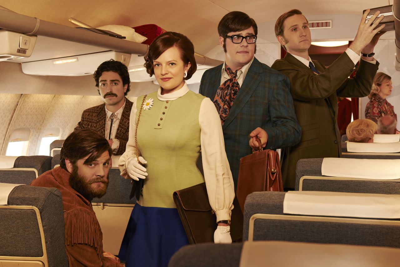 Stan Rizzo (Jay R. Ferguson, seated), Michael Ginsberg (Ben Feldman), Peggy, Harry Crane (Rich Sommer) and Ken Cosgrove (Aaron Staton) on a plane in season 7. Ken is missing the eyepatch he's had to wear since an unfortunate shooting accident in season 6.