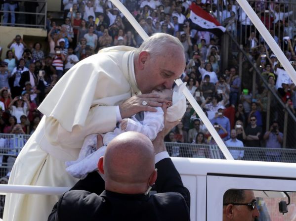 Pope Francis kisses a baby after giving a blessing upon his arrival to lead Mass at the Amman stadium.