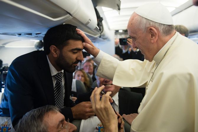 Pope Francis blesses a man as he greets journalists aboard the papal flight on his way to Jordan on May 24.