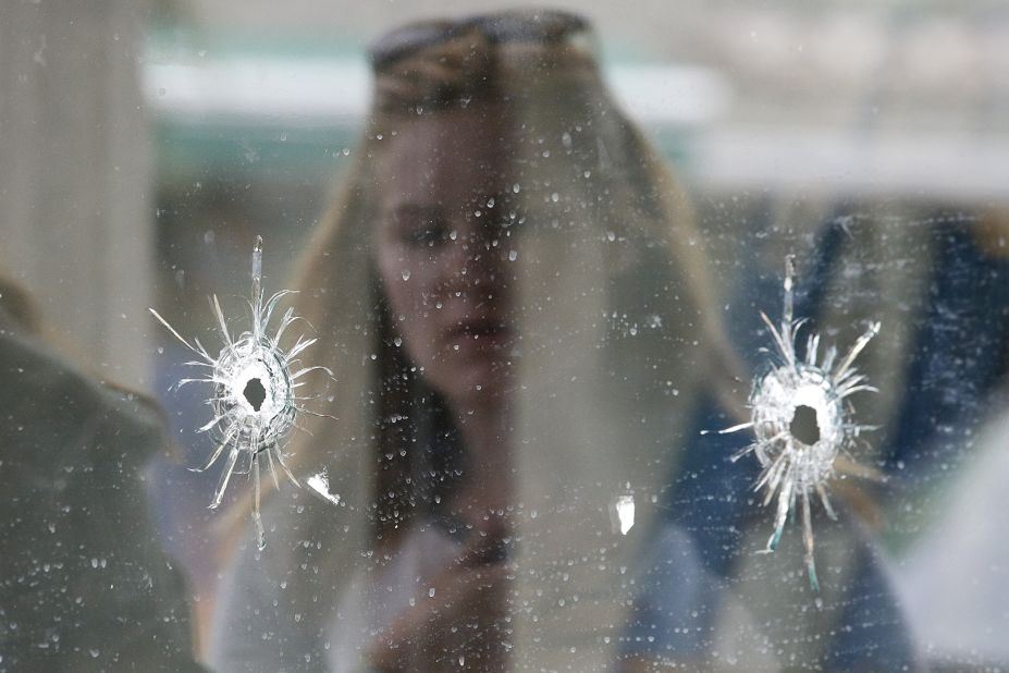 A woman looks at the bullet holes on the window of the deli where part of the shooting spree took place in Isla Vista, California.