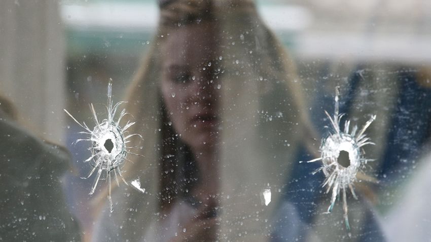 A woman looks at the bullet holes on the window of IV Deli Mark where part of the shooting spree took place in  in Isla Vista, California.