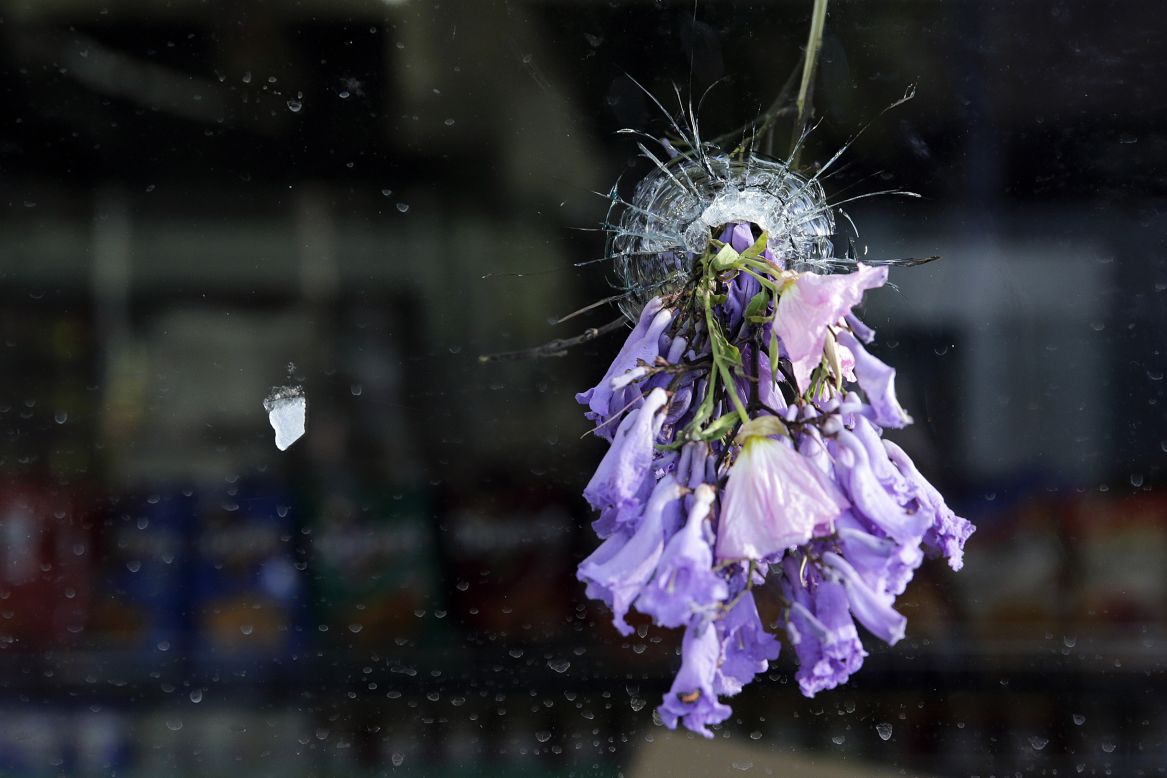 Flowers are placed in a bullet hole in the window of a delicatessen in Isla Vista on May 24.