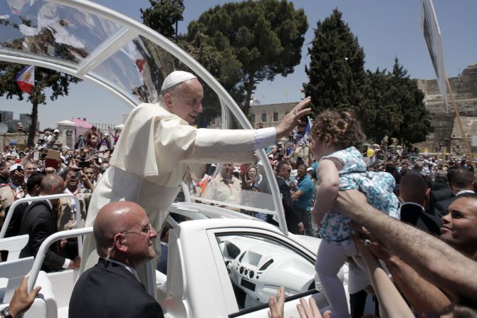 Francis blesses a child from his Popemobile as he leaves Manger Square after presiding over an open-air Mass in the West Bank town of Bethlehem on May 25. Francis extended an invitation Sunday to the leaders of Israel and the Palestinian Authority to travel to the Vatican for a "peace initiative," as he called for a two-state solution to the intractable conflict.