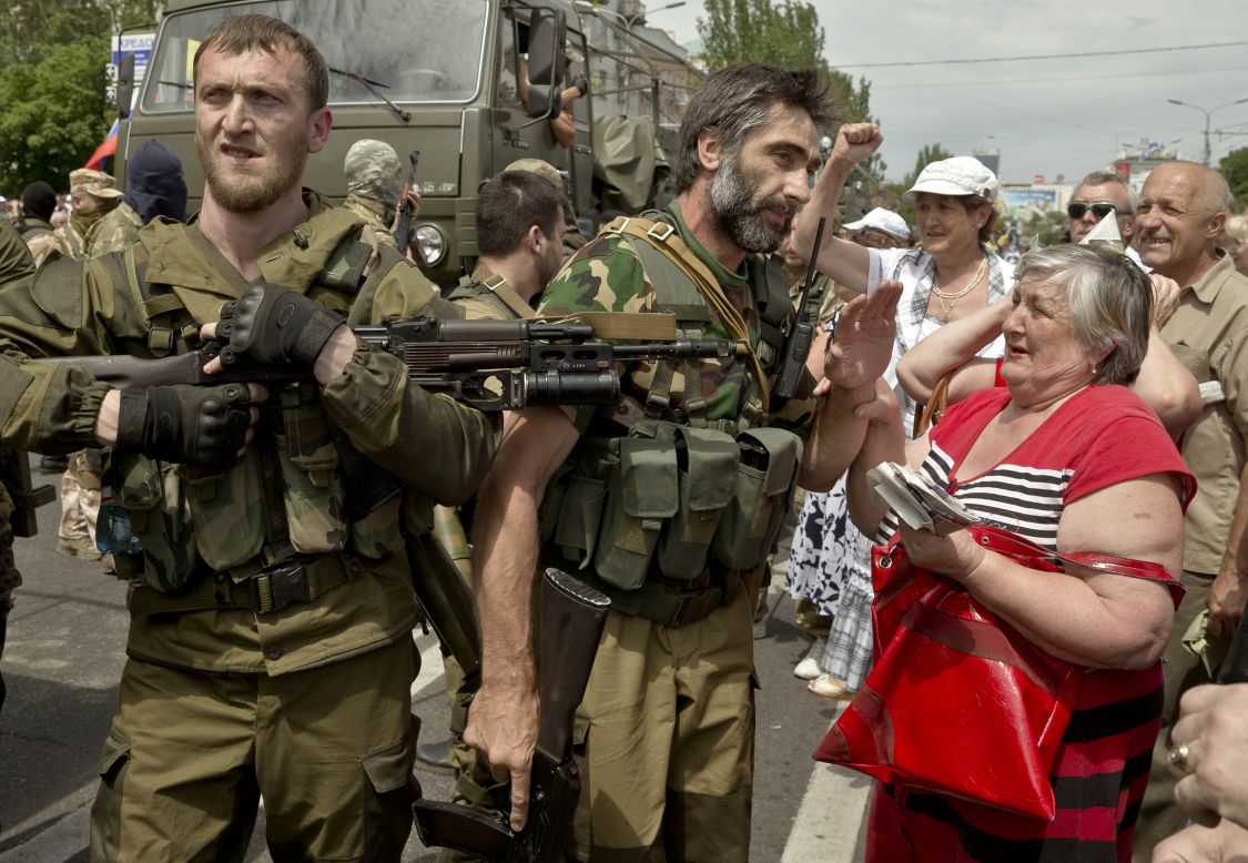 A woman holds the hand of a pro-Russian gunman in Donetsk's Lenin Square on May 25. A large separatist rally was held in Donetsk around lunchtime. The protesters chanted pro-Russian slogans as they were addressed by separatist leaders.