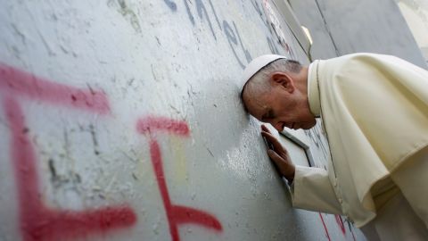 Pope Francis touches the wall that divides Israel from the West Bank, on his way to celebrate a mass in Manger Square next to the Church of the Nativity in Bethlehem 