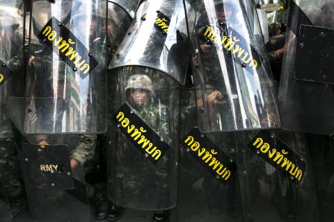 Thai soldiers stand behind their riot shields as protesters threaten them May 25 in Bangkok. 