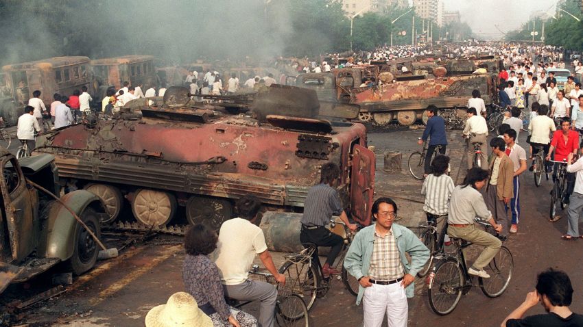 BEIJING, CHINA: Beijing residents inspect the interior of some of over 20 armoured personnel carrier burnt by demonstrators to prevent the troops from moving into Tiananmen Square 04 June 1989. On the night of 03 and 04 June 1989, Tiananmen Square sheltered the last pro-democracy supporters. Chinese troops forcibly marched on the square to end a weeks-long occupation by student protestors, using lethal force to remove opposition it encountered along the way. Hundreds of demonstrators were killed in the crackdown as tanks rolled into the environs of the square. (Photo credit should read MANUEL CENETA/AFP/Getty Images)