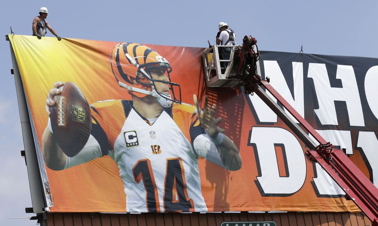 Workers in Covington, Kentucky, stretch out a billboard showing Cincinnati Bengals quarterback Andy Dalton on Thursday, May 22.