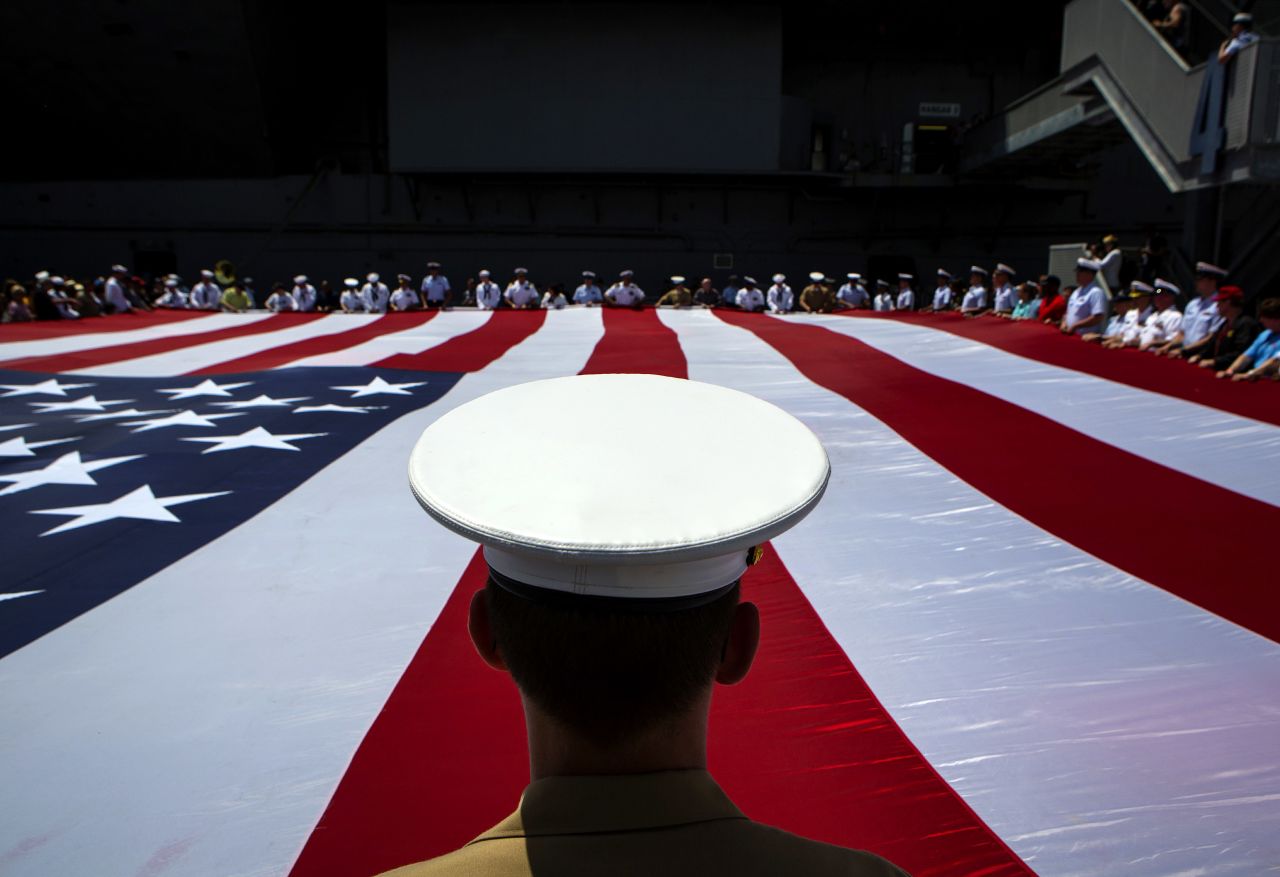 Members of the military unfurl an American flag during a wreath-laying ceremony at the Intrepid Sea, Air & Space Museum in New York on Monday, May 26, 2014.