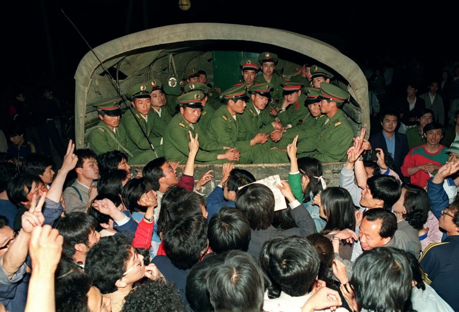 May 20, 1989, pro-democracy demonstrators raise their fists and flash the victory sign while stopping a military truck filled with soldiers on its way to Tiananmen Square.