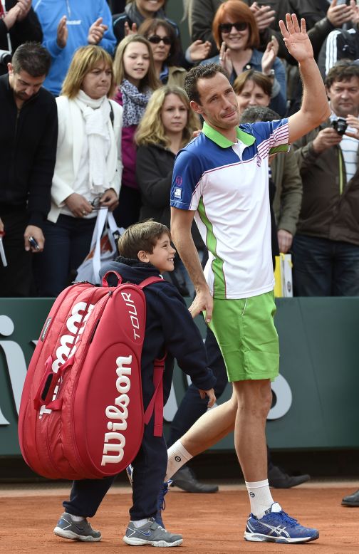 Frenchman Michael Llodra waves goodbye to the crowd with his young son after defeat to Fernando Verdasco in his last professional match at Roland Garros.