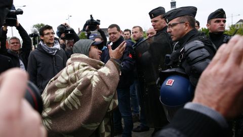 An Afghan migrant argues with French police officers after French authorities started to dismantle makeshift camps in Calais.