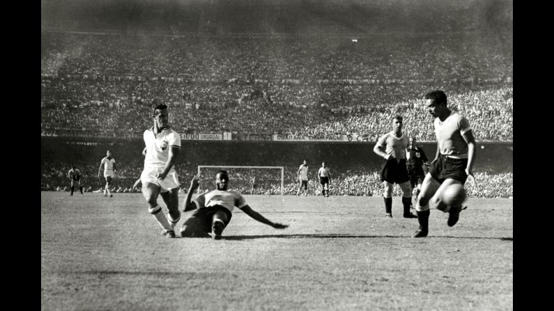 Ademir is challenged by Uruguayan defender Rodriguez Andrade as he shoots a shot wide. There were nearly 200,000 people watching the match at the Maracana Stadium.
