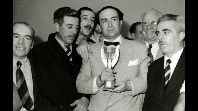 Uruguayan Ambassador Giordano Eccher, surrounded by team officials and journalists, holds the Jules Rimet Trophy, which is given to the World Cup winners.