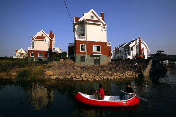 Two men row past houses built in a northern European style at the Luodian development in Huangzho, China.<br /><br />Bianca Bosker recalls from her own experience that many towns are "eerie in their emptiness." But she is quick to add that this certainly isn't a uniform trend across all developments.<br /><br />"When you go to other less well known copycat towns, many of them really are bustling and you see families and kids and a car in every garage," she said. <br /><br />"On the other hand there is a lot of speculation in China's real-estate market. There are a lot of people buying up a lot of property and holding on to it in the hope that the price will go up in the future.<br /><br />"As a result you have developers who are just building acres and acres with tons of people to buy it but nobody to live in it."