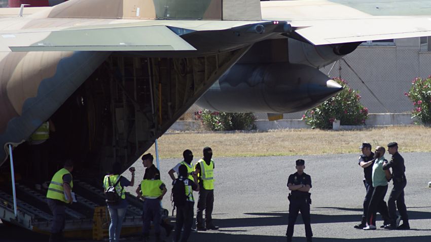 Spanish security forces escort an arrested suspected member of a jihadist cell onto a military aircraft in Spain's north African territory of Melilla on May 30, 2014.
